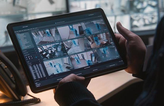 Person holding a tablet displaying multiple live security camera feeds for business monitoring