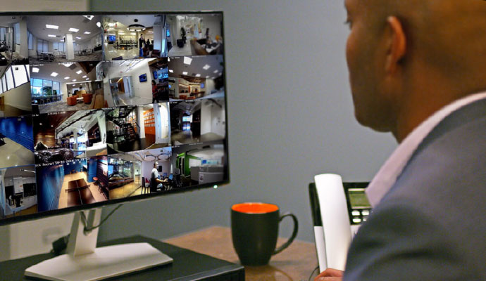 Business professional monitoring multiple live security camera feeds from commercial surveillance system