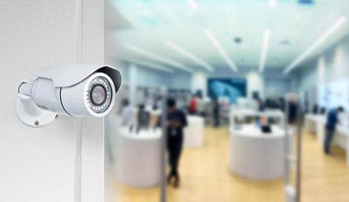 Outdoor security camera mounted on a wall overlooking a modern retail store interior