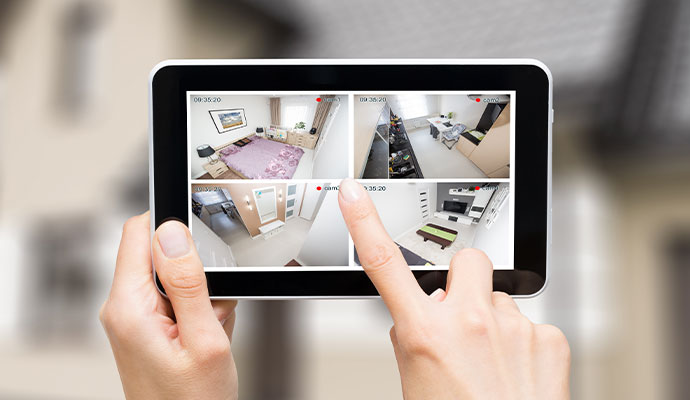 Person monitoring security cameras on tablet