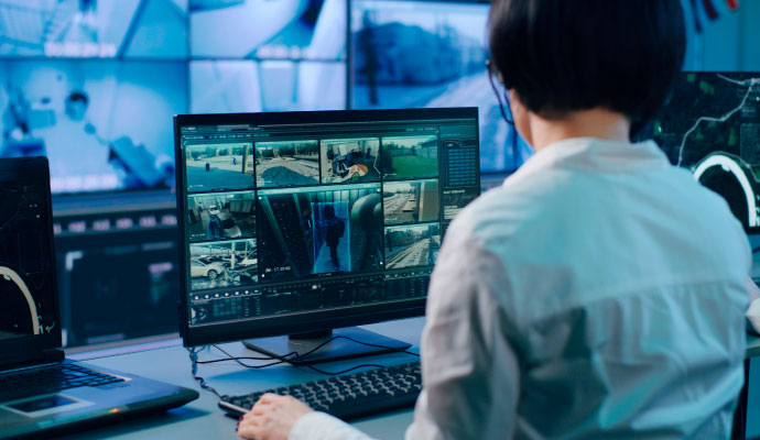 Security surveillance operator monitoring multiple live camera feeds and video analytics systems