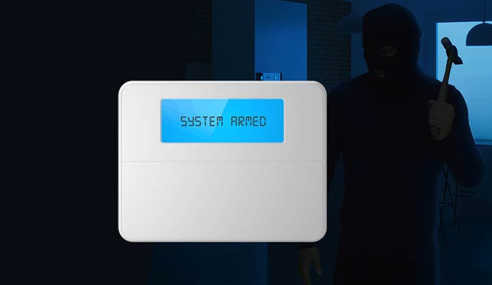 A smart security control panel displaying system armed while an intruder in a mask stands in the background