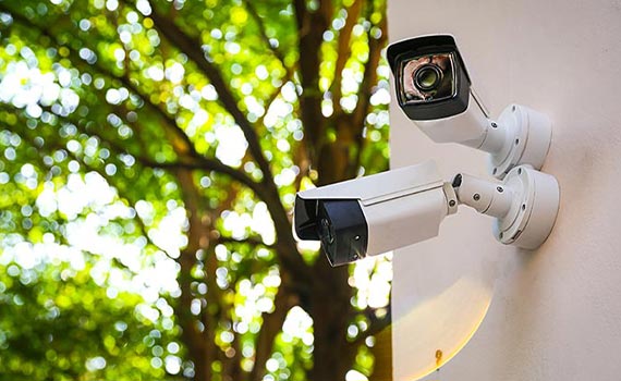 Two security cameras installed outside a home for monitoring and surveillance.