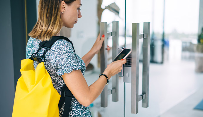 Woman using a smartphone to unlock a glass door